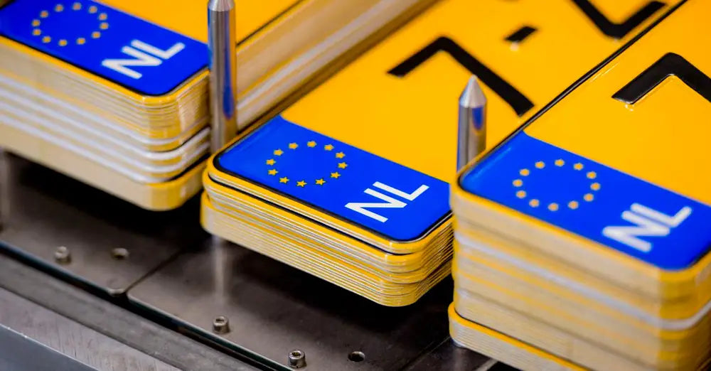 Stapels gele kentekenplaten met blauwe NL-strook in onze fabriek